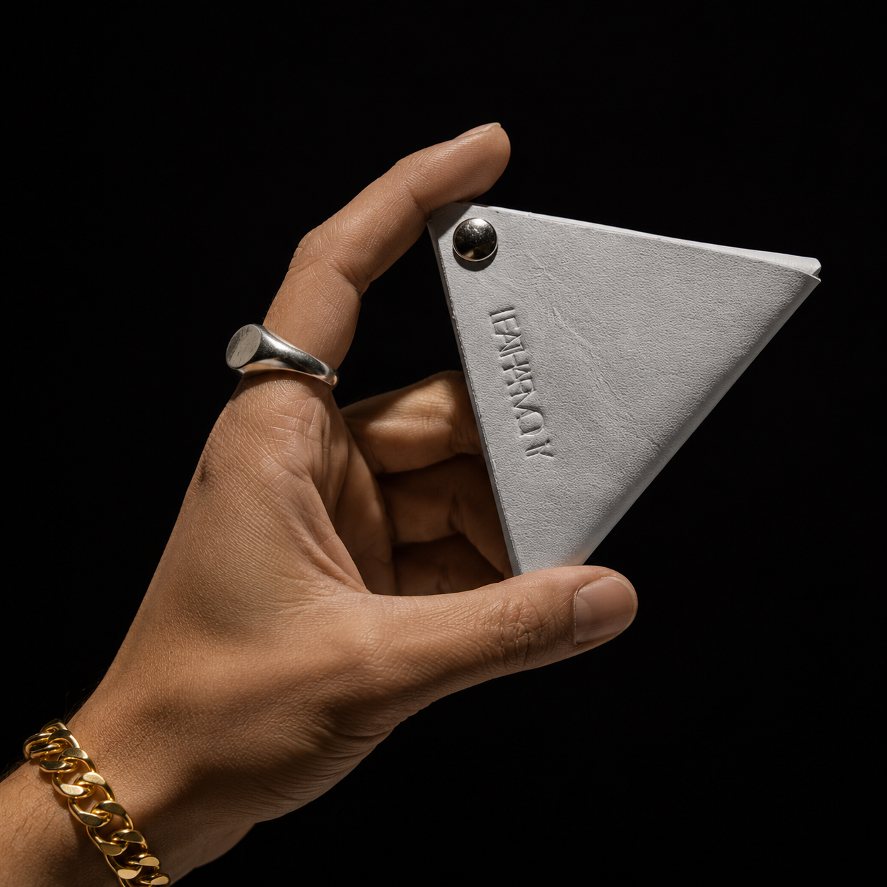 White handmade leather coin pouch held against a black background, highlighting its clean minimalist design.