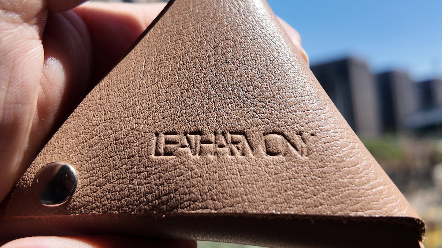 Close-up of the embossed Leatharmony logo on a beige leather coin pouch