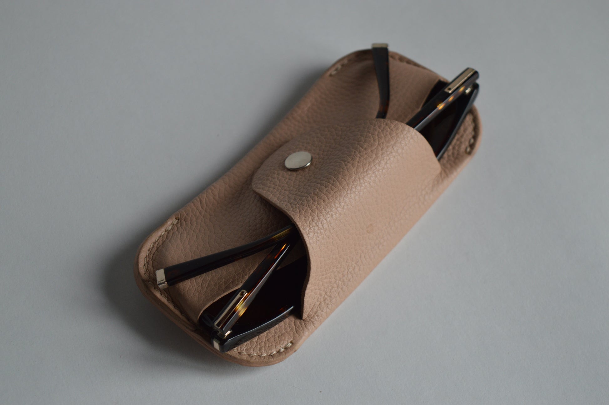 Minimalist beige genuine leather eyewear case photographed on a clean studio background.