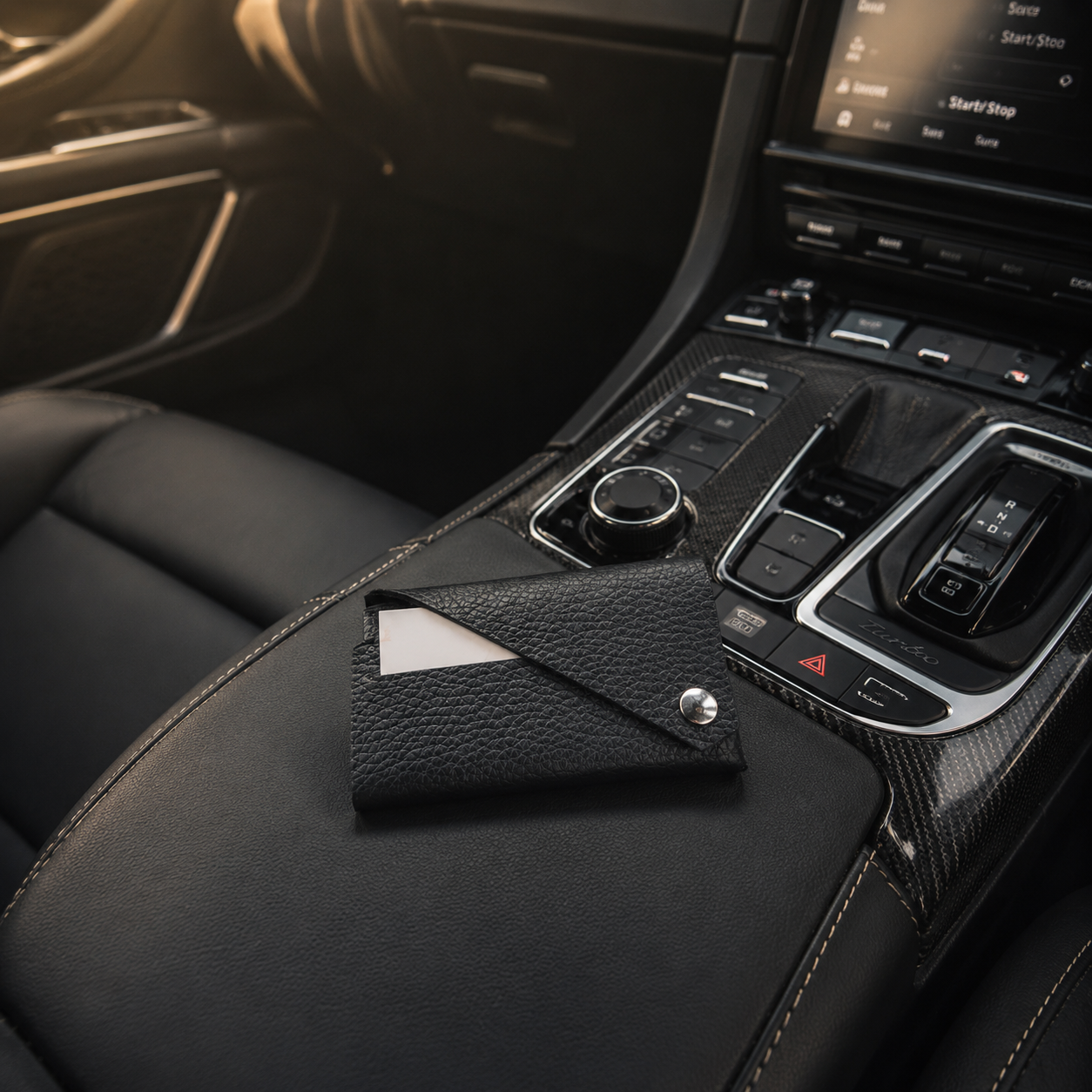 Black leather card holder placed on the centre console of a luxury car.