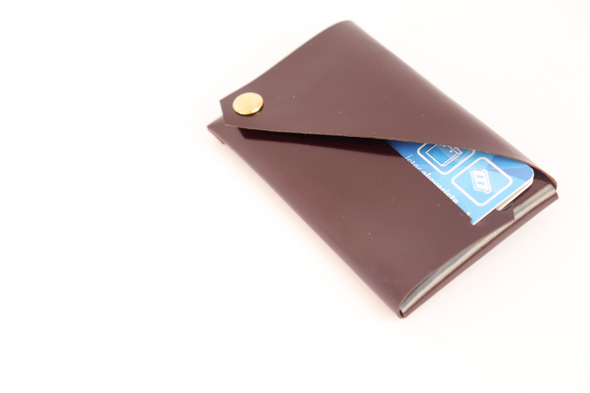 Burgundy patent leather card holder with envelope-style design and metal stud closure.