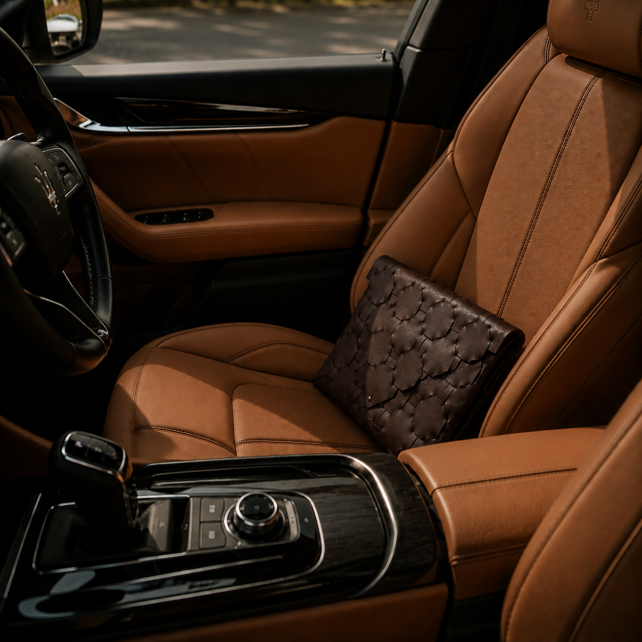 Dark brown geometric leather clutch bag placed on the tan leather seat of a luxury car