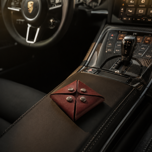 Dark brown genuine leather coin pouch with geometric fold design placed on a luxury car centre console