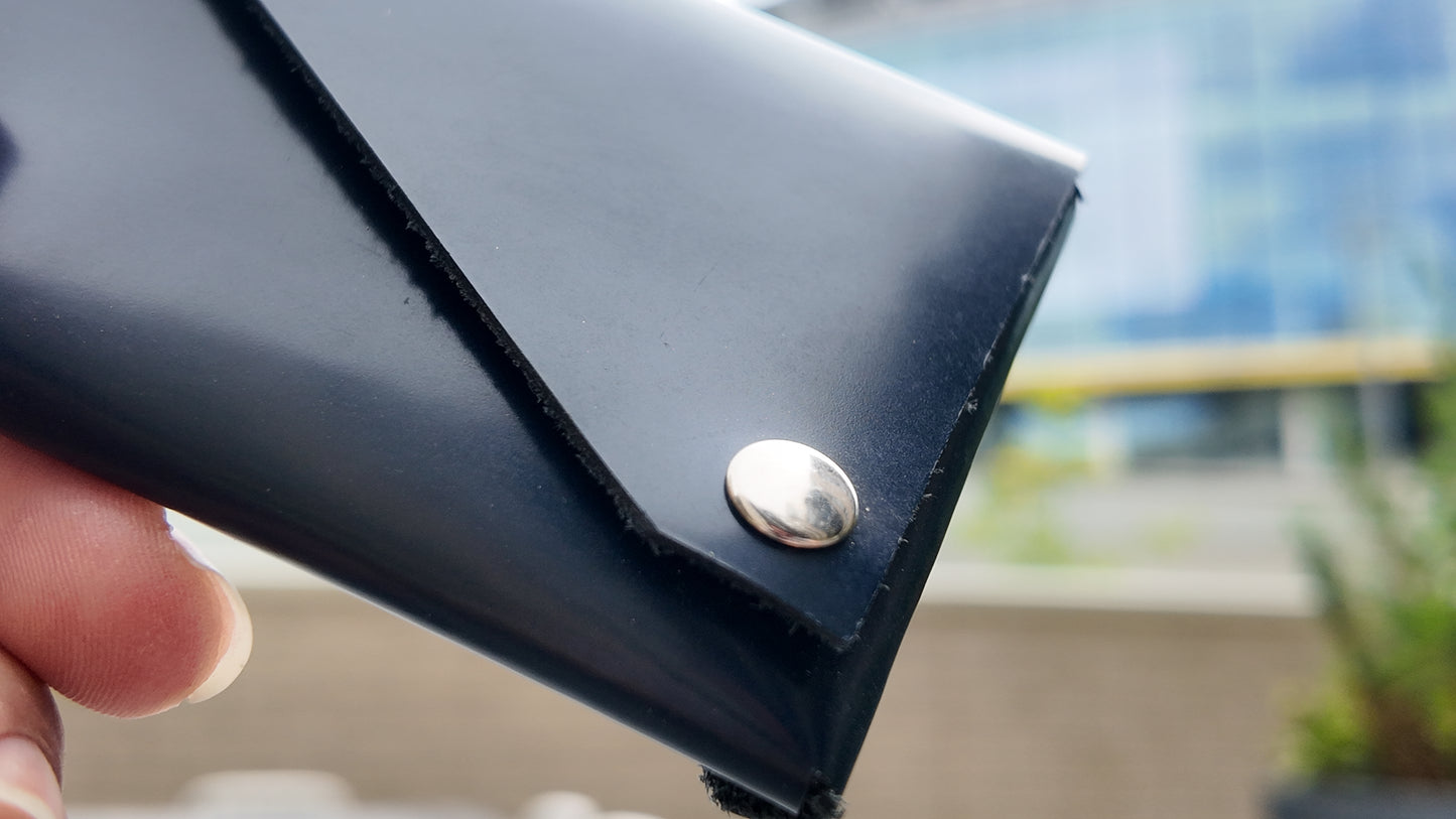 Close-up of the metal snap fastening on a navy patent leather wallet