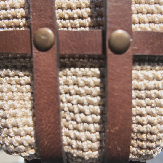 Close-up video of a cream crochet and brown leather crossbody bag showcasing the woven texture, leather straps and brass rivet details.