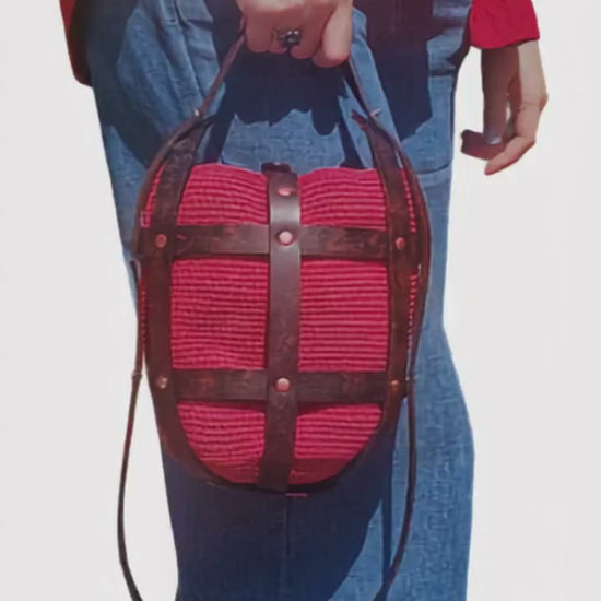 Video of a woman carrying a handmade red crochet leather crossbody bag while walking in casual everyday style.