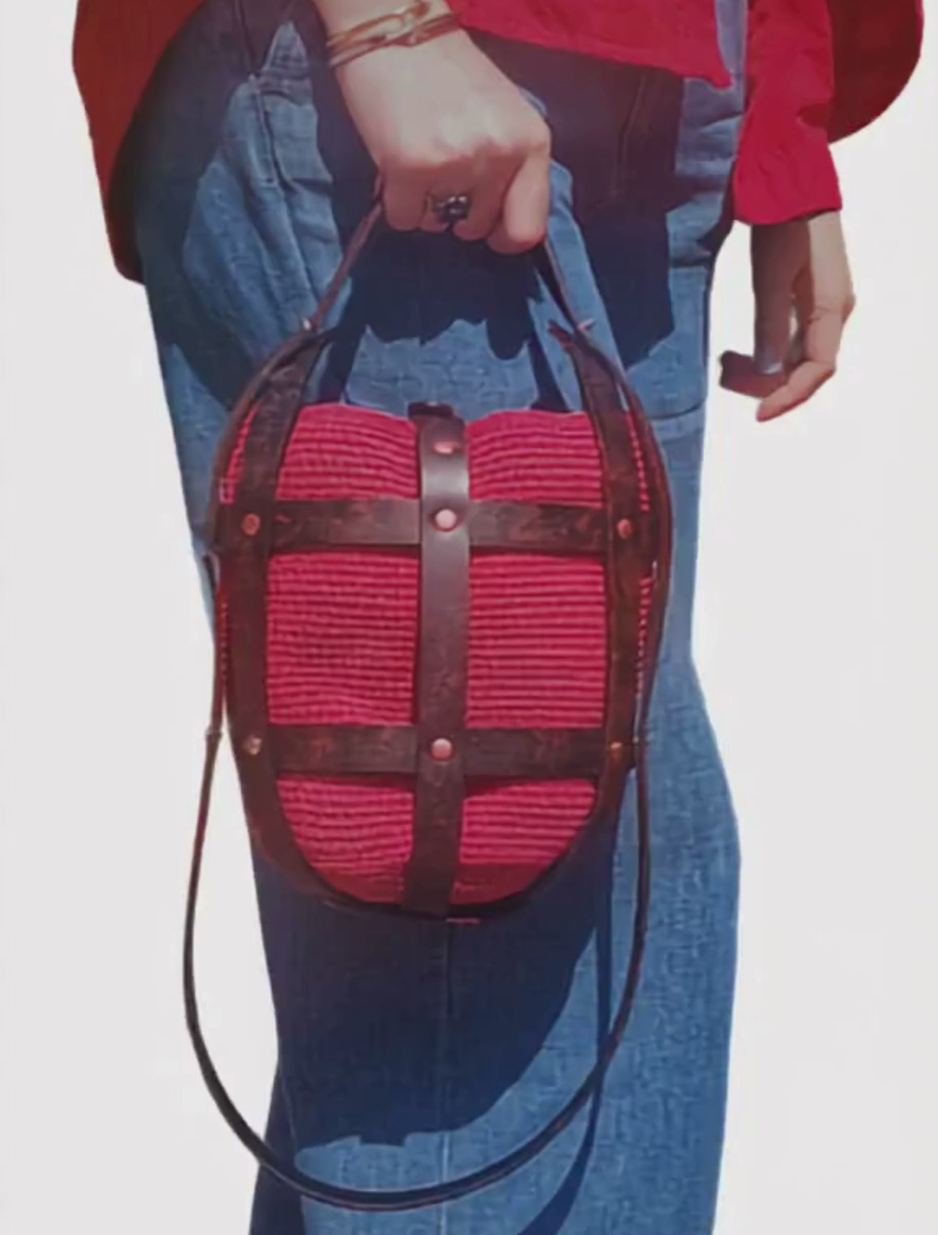 Video of a woman carrying a handmade red crochet leather crossbody bag while walking in casual everyday style.