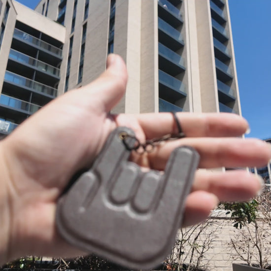 Handmade dark brown leather hand keychain by LEATHARMONY showcased outdoors in natural sunlight, highlighting the premium leather texture and handcrafted details.