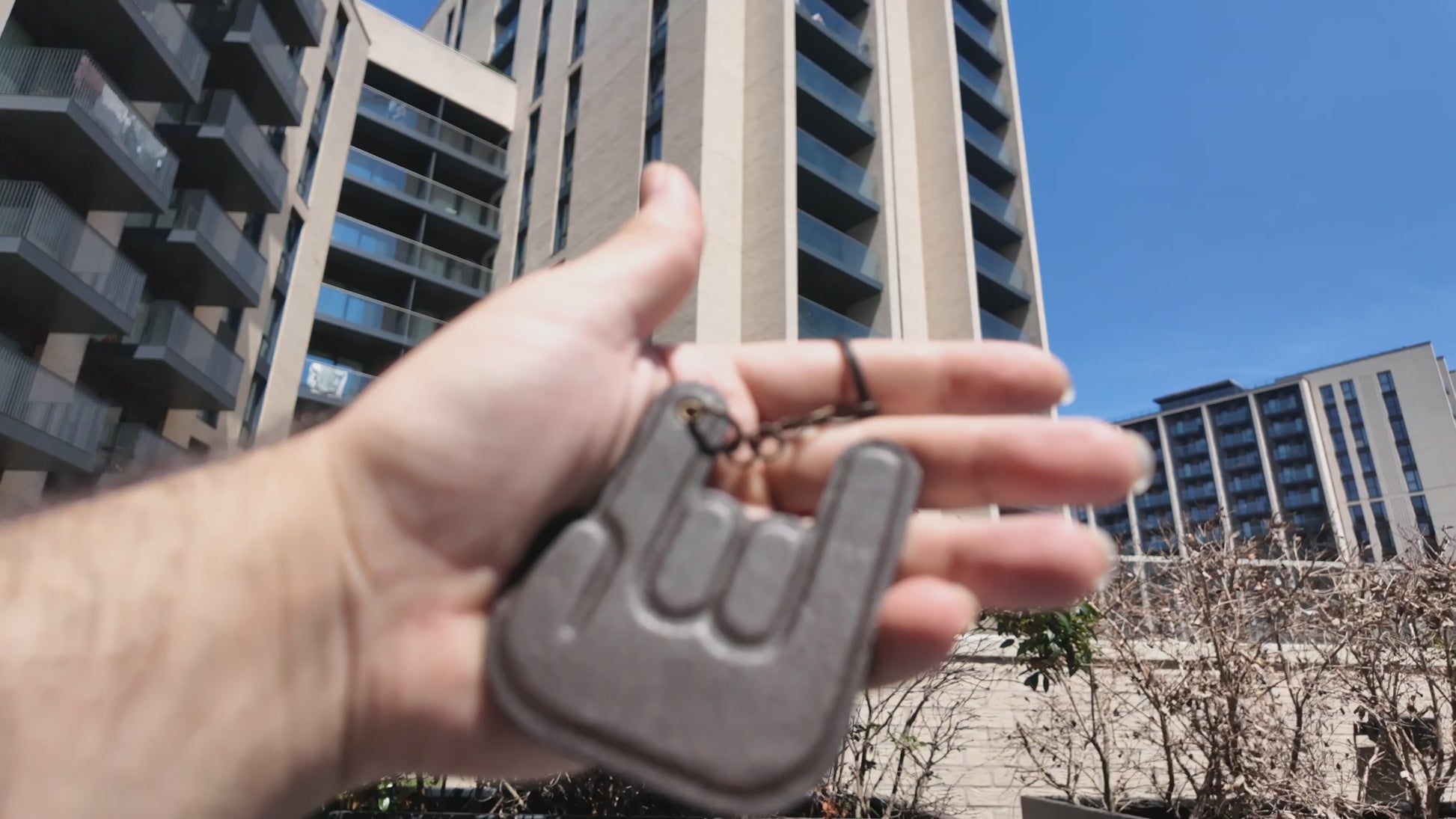 Handmade dark brown leather hand keychain by LEATHARMONY showcased outdoors in natural sunlight, highlighting the premium leather texture and handcrafted details.