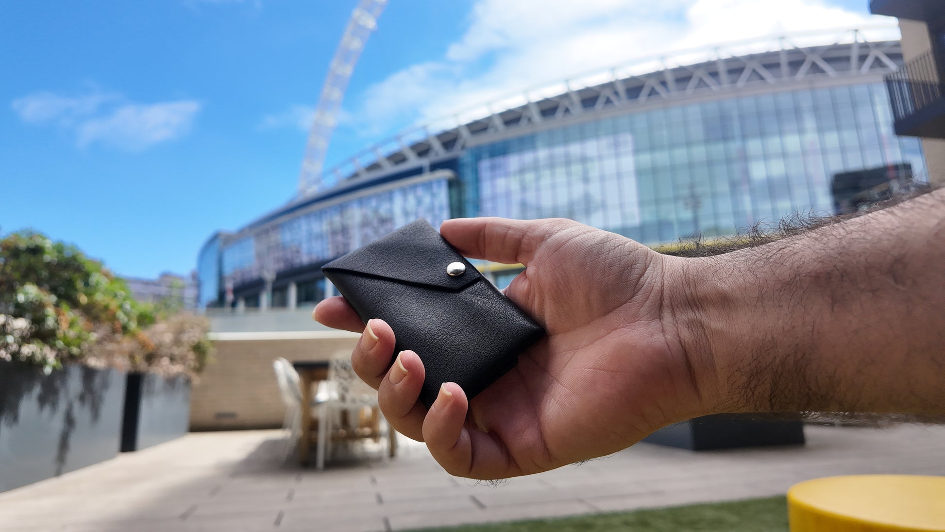 Slim black genuine leather envelope card holder held in hand in an outdoor urban setting