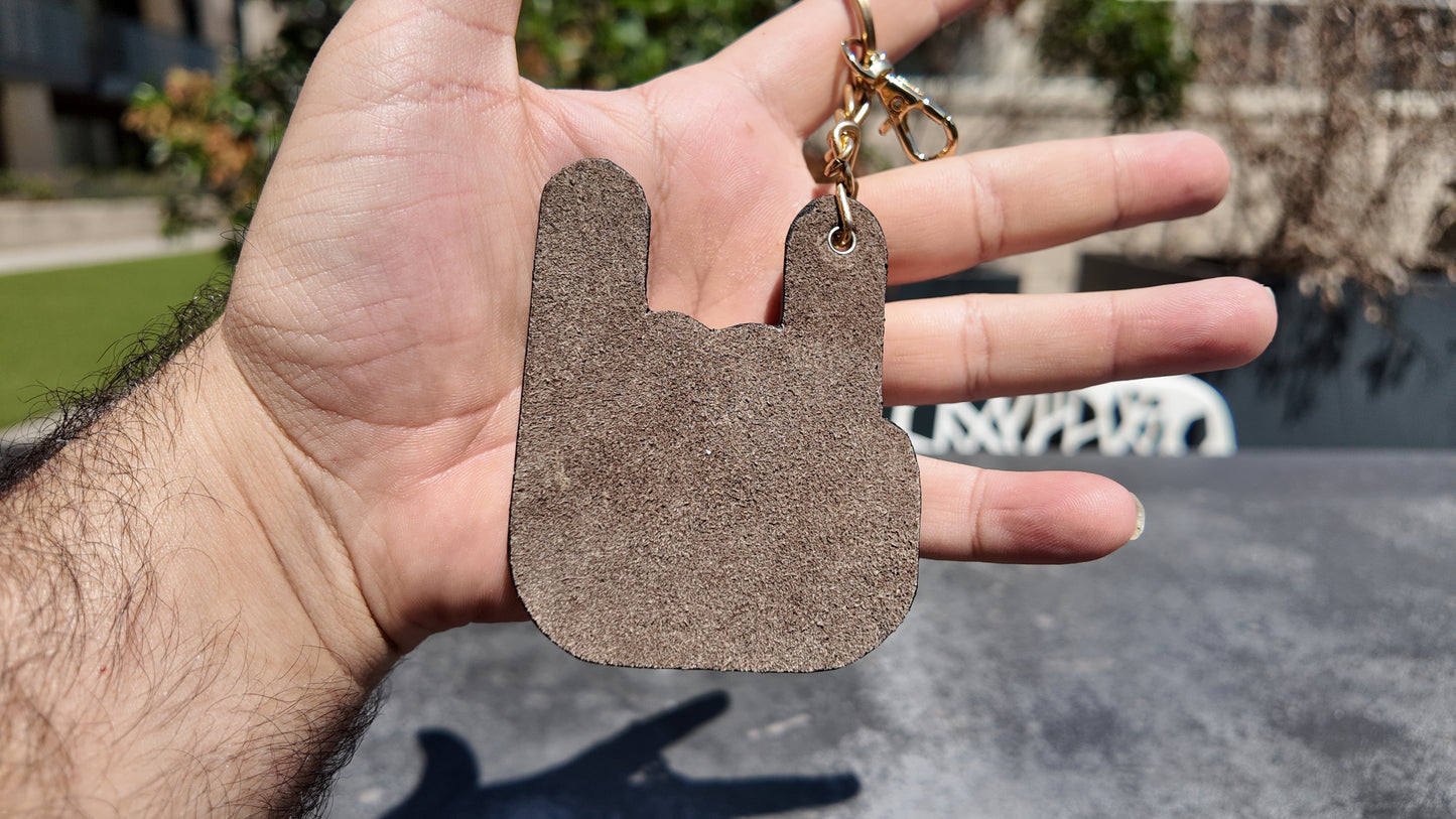 Back view of a handmade taupe genuine leather keychain highlighting its soft suede finish and craftsmanship.