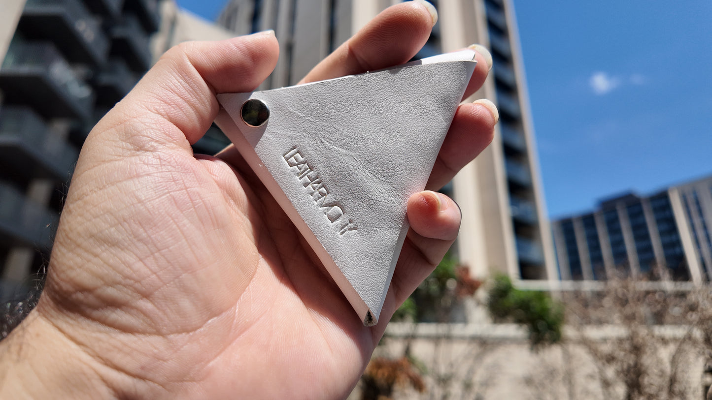 Close-up of a handmade white leather coin pouch featuring the embossed Leatharmony logo.