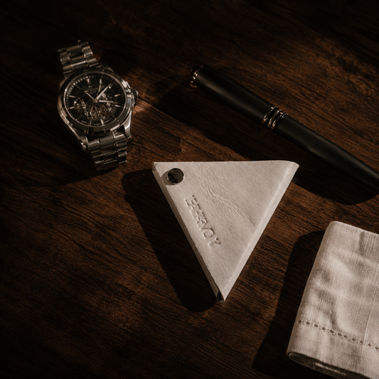 Handmade white genuine leather coin pouch displayed on a wooden desk with a luxury watch and pen.
